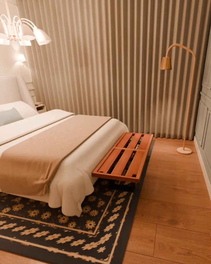 Quarto de casal à noite visto da porta: o pé de uma cama queen com manta caramelo, um banco baixo de ripas largas de madeira logo depois dela, sobre um tapete azul-marinho com flores, uma luminária de chão em arco no canto e uma cortina clara cobrindo a parede da janela